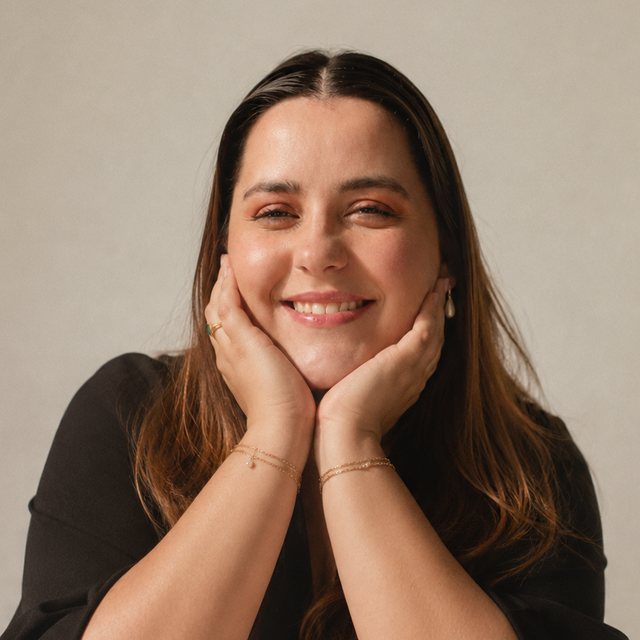 Giovana, sorrindo, com o rosto apoiado nas mãos
